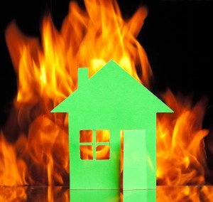 Paper house in fire on a black background concept